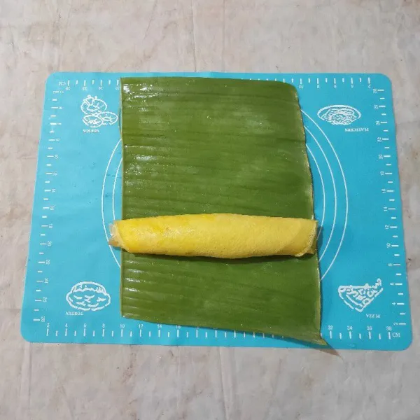 Letakkan rolade mentah di atas satu lembar daun pisang, lalu gulung kembali.