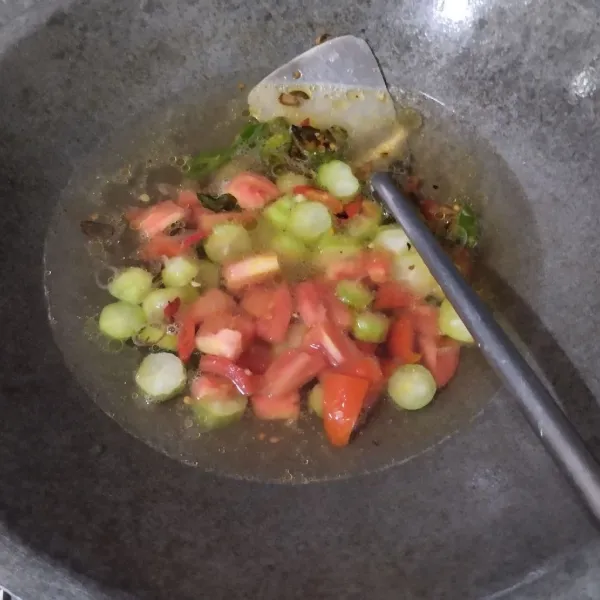 Tuang air, biarkan mendidih lalu masukkan tomat dan belimbing wuluh, biarkan hingga layu.