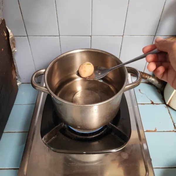 Siapkan panci yang berisi air panas. Bentuk adonan menggunakan dua sendok. Masukkan bulatan bakso ke dalam panci.