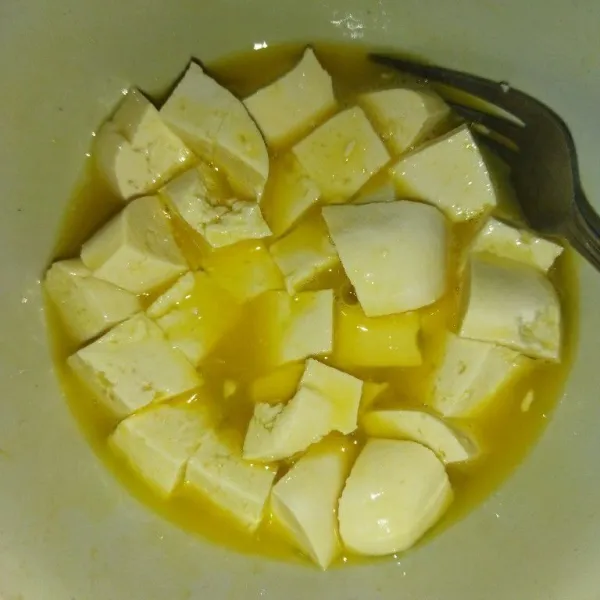 Siapkan mangkuk, masukkan telur, garam dan kaldu bubuk, lalu kocok, masukkan potongan tahu, aduk rata.