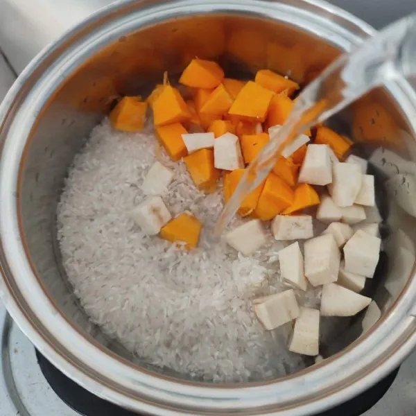 Masukkan beras, ketela dan labu kuning ke dalam panci. Tambahkan air, masak dengan api kecil.