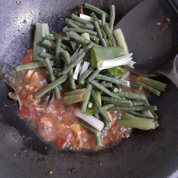 Tuangkan air mineral, masak hingga mendidih. Tambahkan gula pasir, garam dan penyedap, aduk rata. Besarkan api, masukkan kacang panjang dan daun bawang, aduk rata. Masak hingga kacang panjang setengah matang.