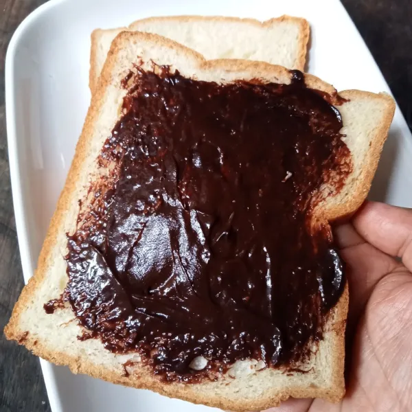 Oles roti tawar dengan selai cokelat,. lalu tangkupkan roti.