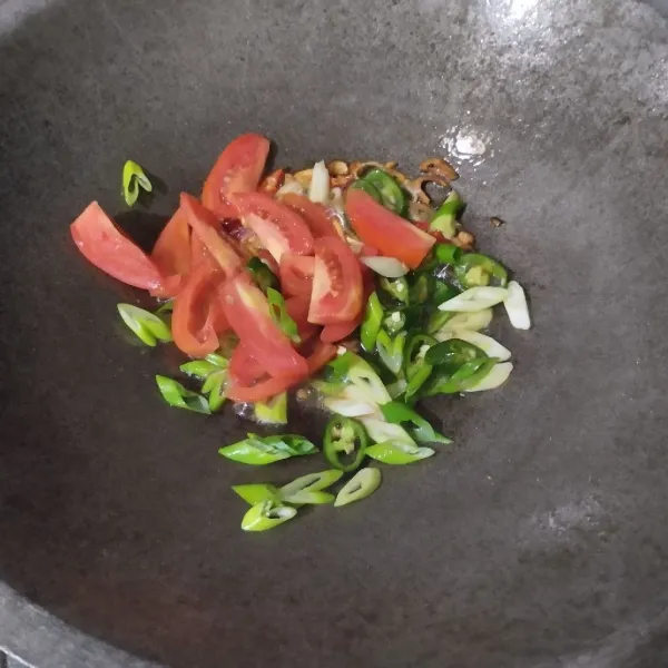 Masukkan tomat, cabai hijau dan daun bawang. Aduk hingga layu.