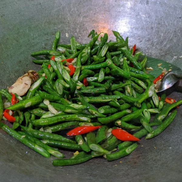 Masukkan kacang panjang, tambahkan secukupnya garam, kaldu bubuk, lada bubuk dan gula pasir. Aduk merata, tambahkan sedikit air, masak hingga kacang panjang setengah layu.