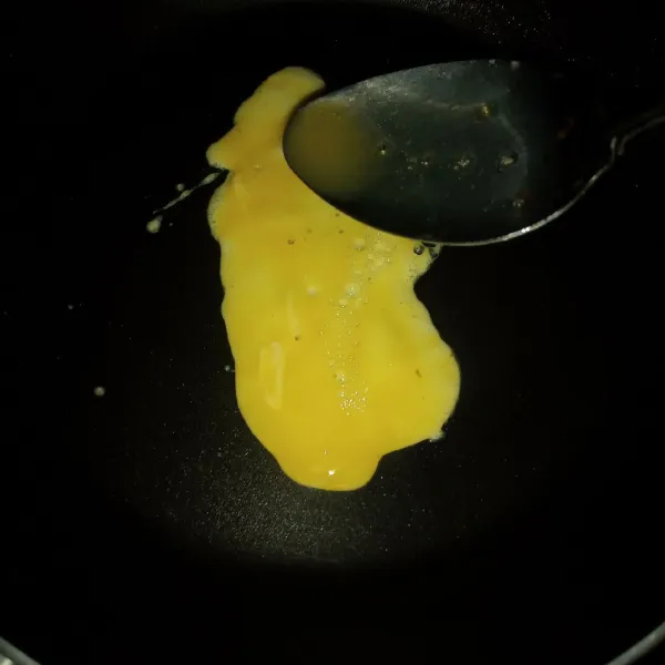 Setelah wajan panas, tuang telur kocok memanjang.