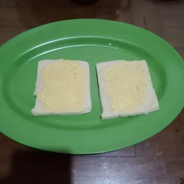 Oles margarin di atas roti.