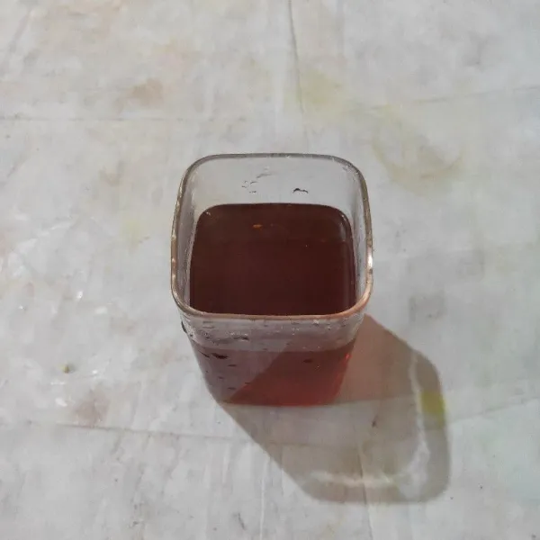Tuang air rebusan teh ke dalam gelas saji.