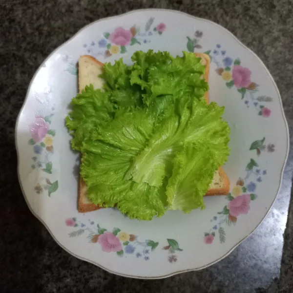 Siapkan roti tawar, tata daun selada di atasnya.