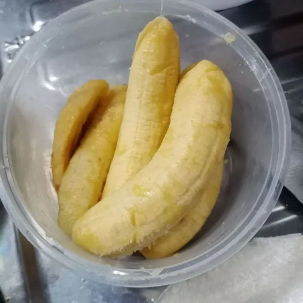 Kupas pisang kemudian belah menjadi 2 bagian.