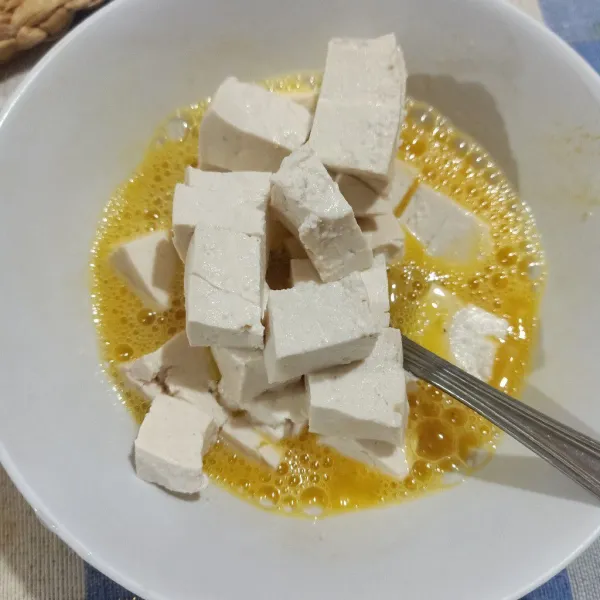 Kocok lepas telur, beri bumbu lalu campur dengan tahu.