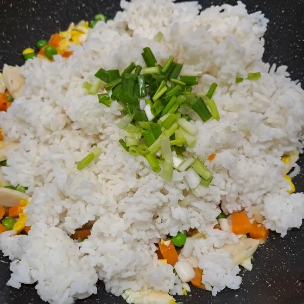 Masukkan nasi putih dan daun bawang. Aduk rata dengan tumisan sayur.