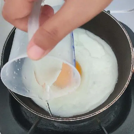 Setelah putih telur mulai berubah warna, siram bagian pinggir dengan air.