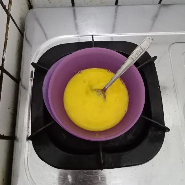 Pecahkan telur dalam mangkuk. Beri kaldu bubuk. Aduk rata.