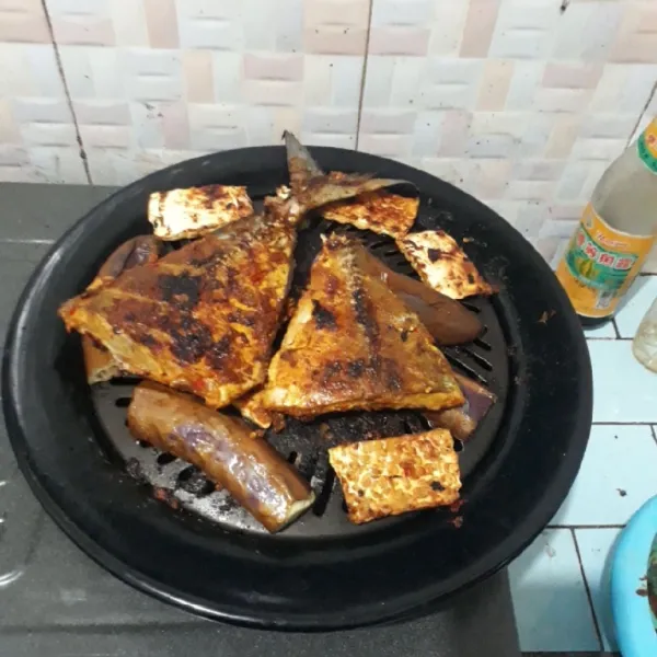 Bakar ikan dengan api kecil sambil dioles dengan sisa bumbu. Bakar hingga matang. Iris tempe dan bagi terong menjadi 4 bagian, bakar dengan api kecil.