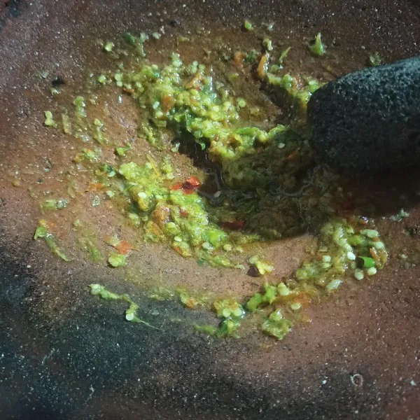 Pindahkan ke cobek dan tambahkan garam dan kaldu bubuk, ulek halus lalu siram dengan minyak panas sisa menggoreng cabai tadi lalu ratakan.