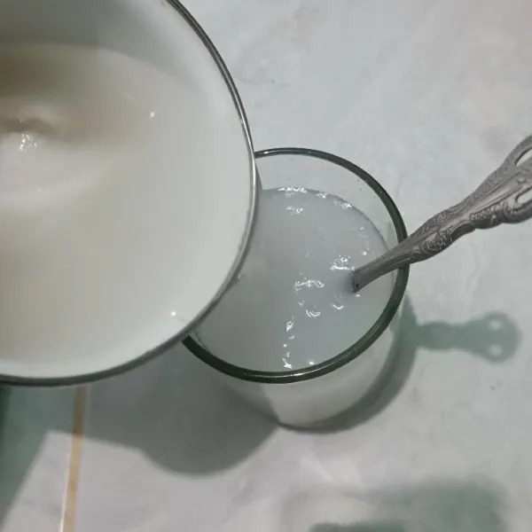 Bagi air kelapa beserta isinya menjadi 4 bagian lalu tuang ke dalam gelas.