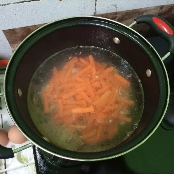 Tambahkan air, tunggu sampai mendidih, lalu masukkan wortel. Masak hingga wortel agak matang.