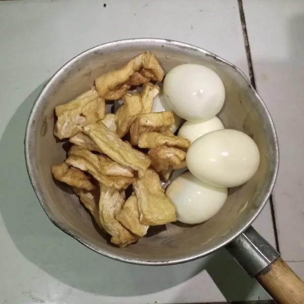 Bersihkan telur, lalu rebus dan kupas cangkangnya. Untuk tahu putihnya dipotong-potong terlebih dahulu, lalu goreng setengah matang.
