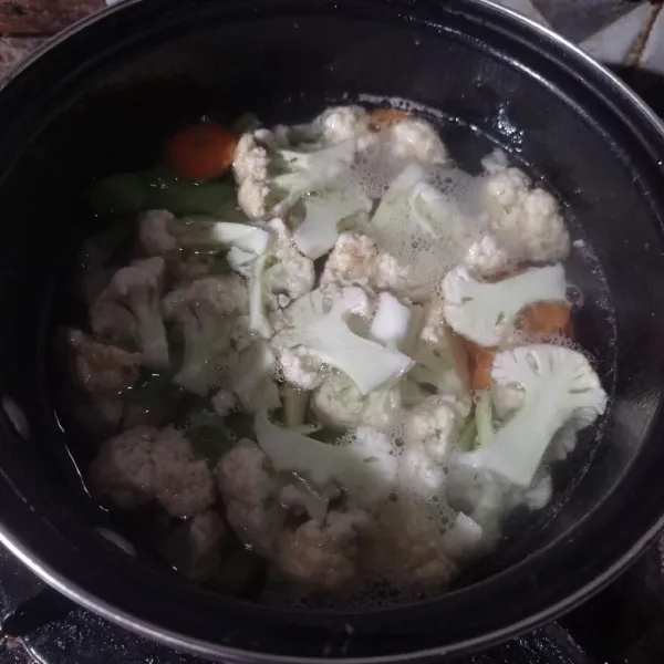 Tuang air masak sampai mendidih, lalu masukkan kembang kol, wortel, garam, gula, lada dan kaldu bubuk masak setengah matang.