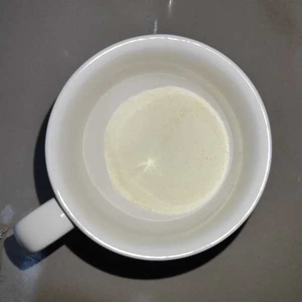 Tuang susu skim bubuk ke gelas saji
