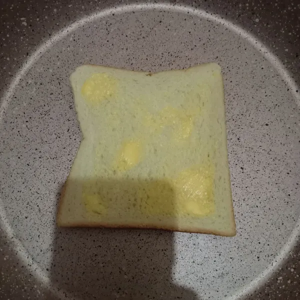 Olesi kedua sisi roti dengan margarin.