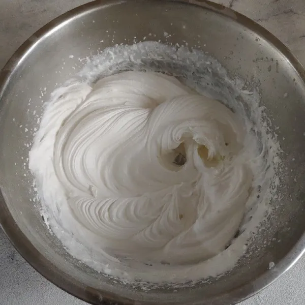 Membuat toping, masukkan bubuk whipping cream ke dalam wadah dan tambahkan air es. Mixer selama 5 sampai 7 menit sampai menjadi kaku.