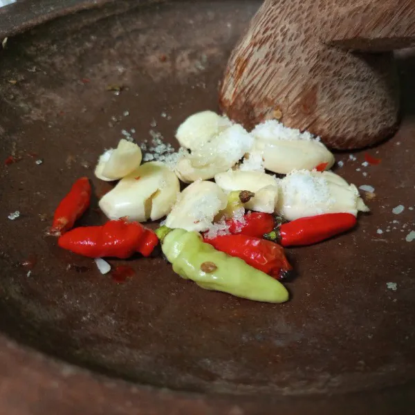 Ulek kasar bawang dan cabe dengan tambahan garam secukupnya dalam cobek.