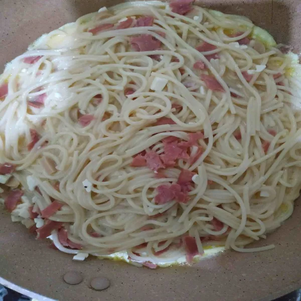 Panaskan pan, kemudian tuang semua campuran spaghetti di pan. Panggang dengan api kecil hingga kedua sisi matang