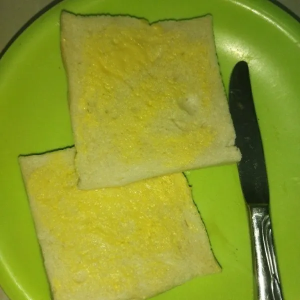 Siapkan roti tawar, lalu oles kedua sisi roti tawar dengan margarin.
