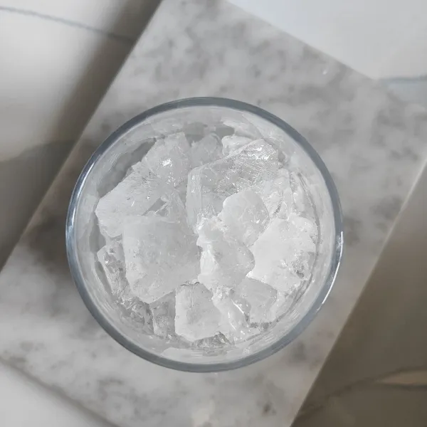 Siapkan gelas saji, masukkan es batu ke dalam gelas saji.