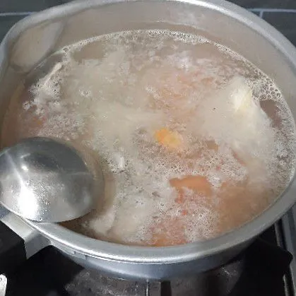 Panaskan air, masukkan tulang ayam dan wortel, masak hingga matang.