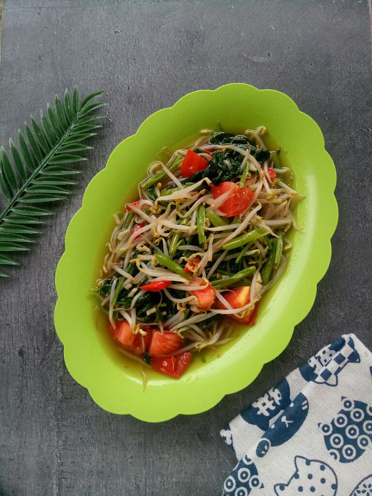 Oseng kangkung tahu dalam piring saji dengan latar belakang meja makan