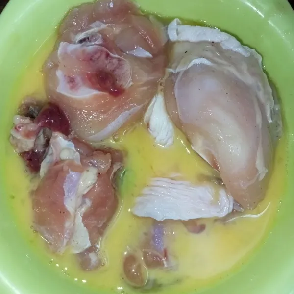 Celupkan ayam ke dalam telur kocok, bolak balik ayam supaya telur merata pada ayam.