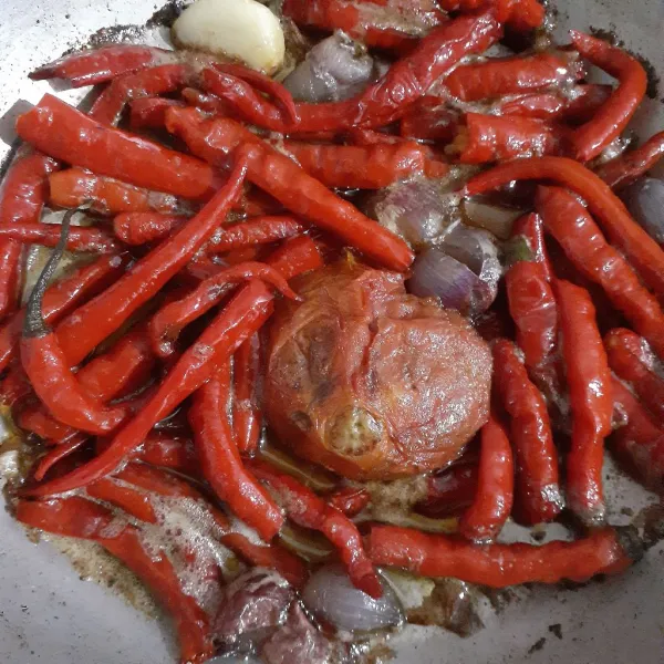 Panaskan 50 ml minyak sayur dengan api sedang dan tumis cabe merah, tomat, bawang merah dan bawang putih hingga layu.