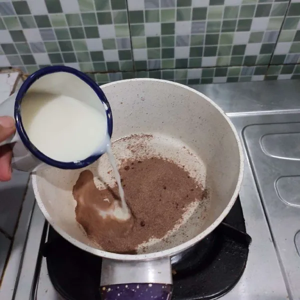 Masukkan coklat bubuk, gula pasir, serta susu cair ke dalam milk pan, kemudian aduk rata, nyalakan api kecil.