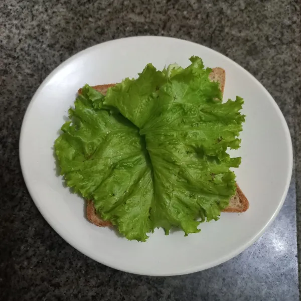 Siapkan roti tawar, alasi dengan daun selada.
