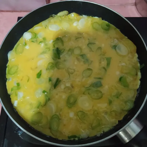 Tuang kocokan telur, ratakan. Tutup dan masak dengan api kecil sampai bagian bawahnya matang.