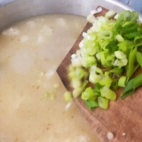 Masukkan nasi ke dalam air kaldu, aduk hingga mengental, tambahkan irisan bawang prei.