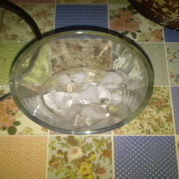 Siapkan secukupnya es batu dalam gelas saji.
