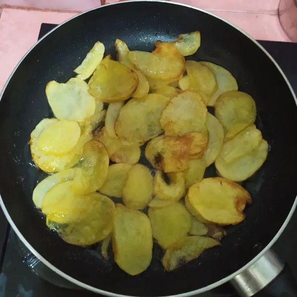 Iris kentang tipis-tipis.
Panaskan sedikit minyak, tata kentang lalu masak dengan api kecil. Jika sudah agak kecokelatan, balik. Masak hingga matang.