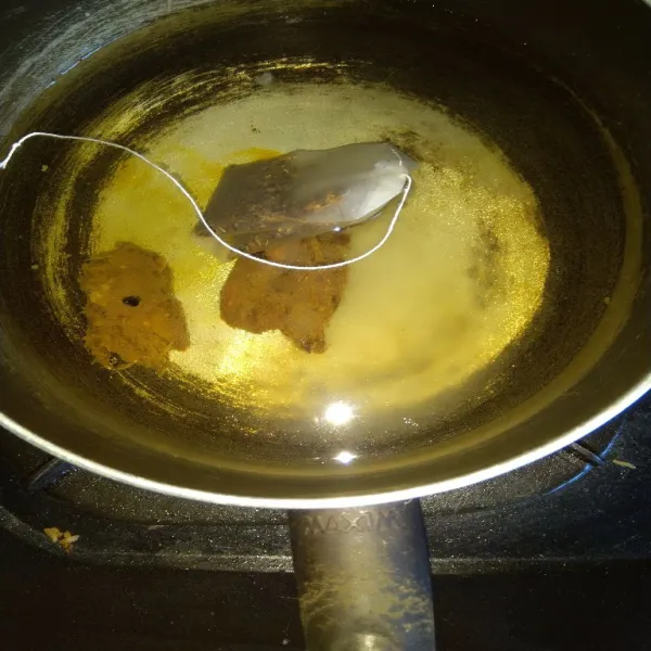 Masukkan teh celup, asam jawa dan gula ke dalam air di panci.