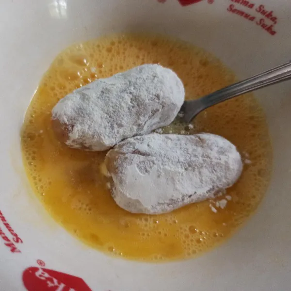 Gulingkan adonan kroket ke dalam tepung terigu kemudian celupkan ke dalam telur.