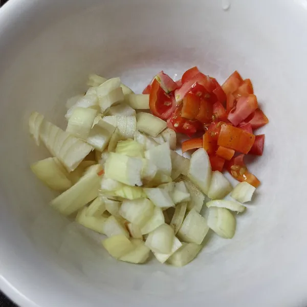 Potong-potong bawang bombay dan tomat.
