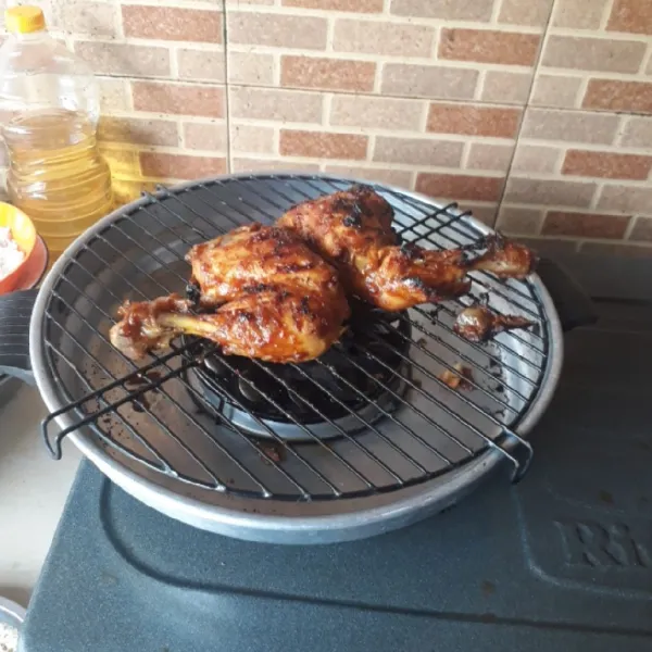 Bakar ayam dengan api kecil hingga matang. Sajikan ayam bakar dengan pelengkap sambal terasi, timun dan daun kemangi.