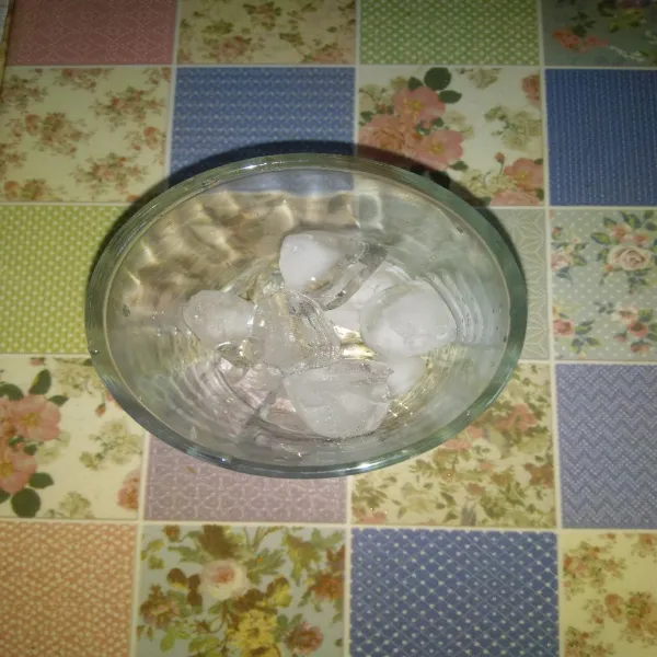 Siapkan secukupnya es batu dalam gelas saji.