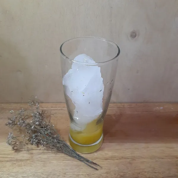 Pada gelas saji, tuang sari jeruk kasturi, tambahkan es batu.