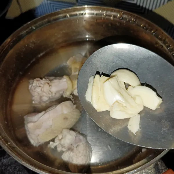 Buang air rebusan ayam, lalu ganti dengan air yang baru dan tambahkan juga bawang putih.