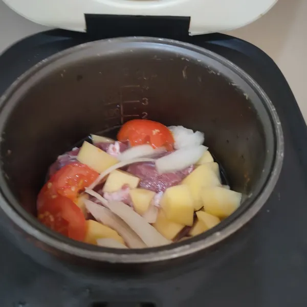 Campurkan di pan, daging sapi, bawang bombay, kentang, tomat merah dan air.