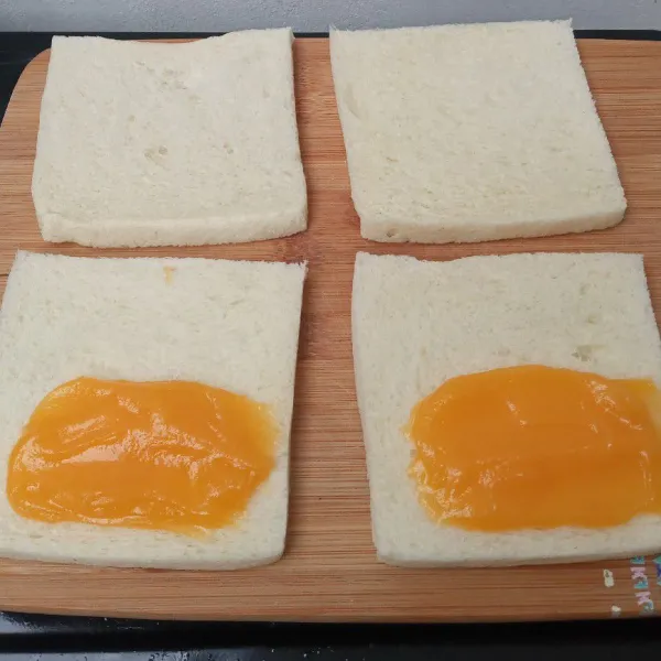 Siapkan roti tawar lalu oles selai di salah satu sisi roti